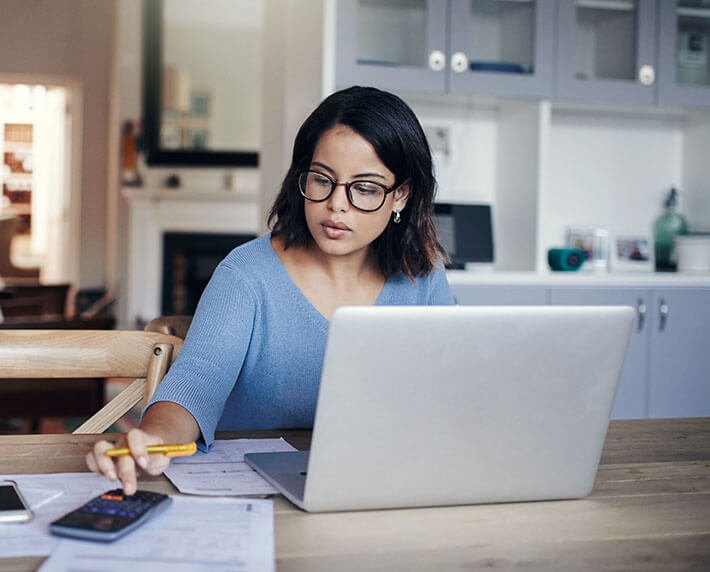Woman using a calculator to compare life insurance with other investments