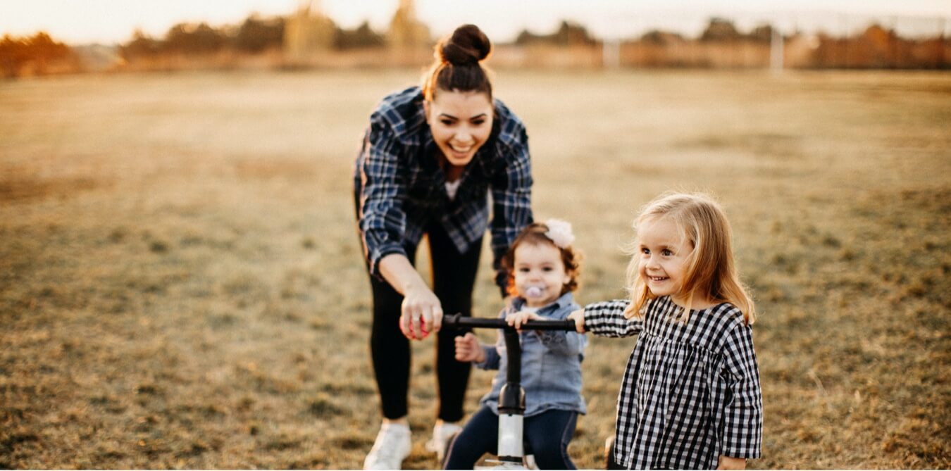Mother with her two young children outdoors - level term life insurance protects young families with locked-in premiums