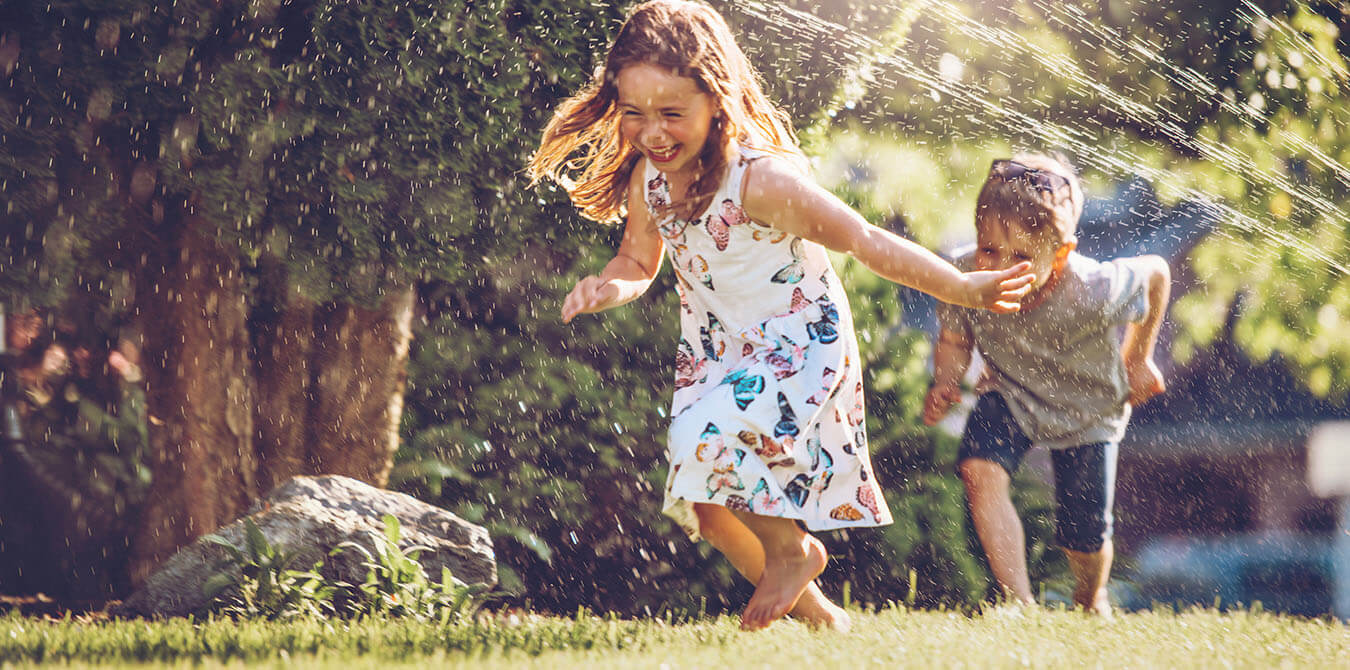children running through sprinklers